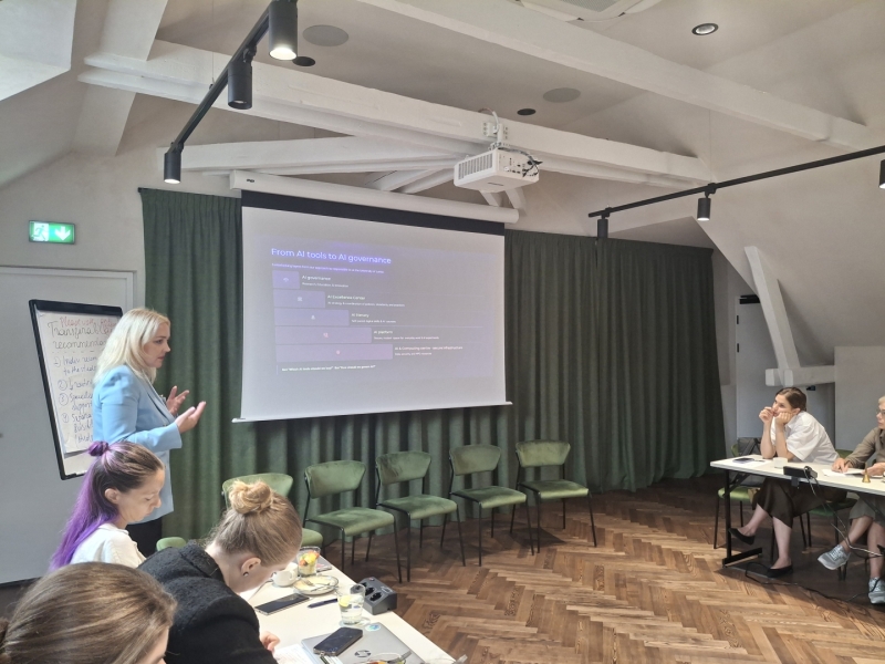 Lektore stāv pie projektora ekrāna un vada prezentāciju par mākslīgā intelekta pārvaldību.
