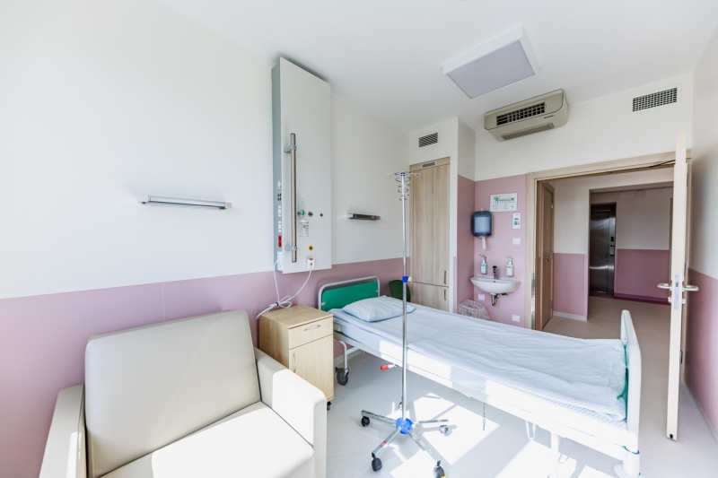 Gaiša, moderna slimnīcas palāta ar vienu pacienta gultu telpas centrā. 