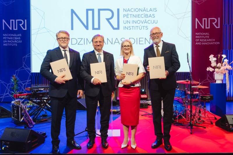 NIRI atklāšana, četri cilvēki rindā stāv ar plakātiem rokās