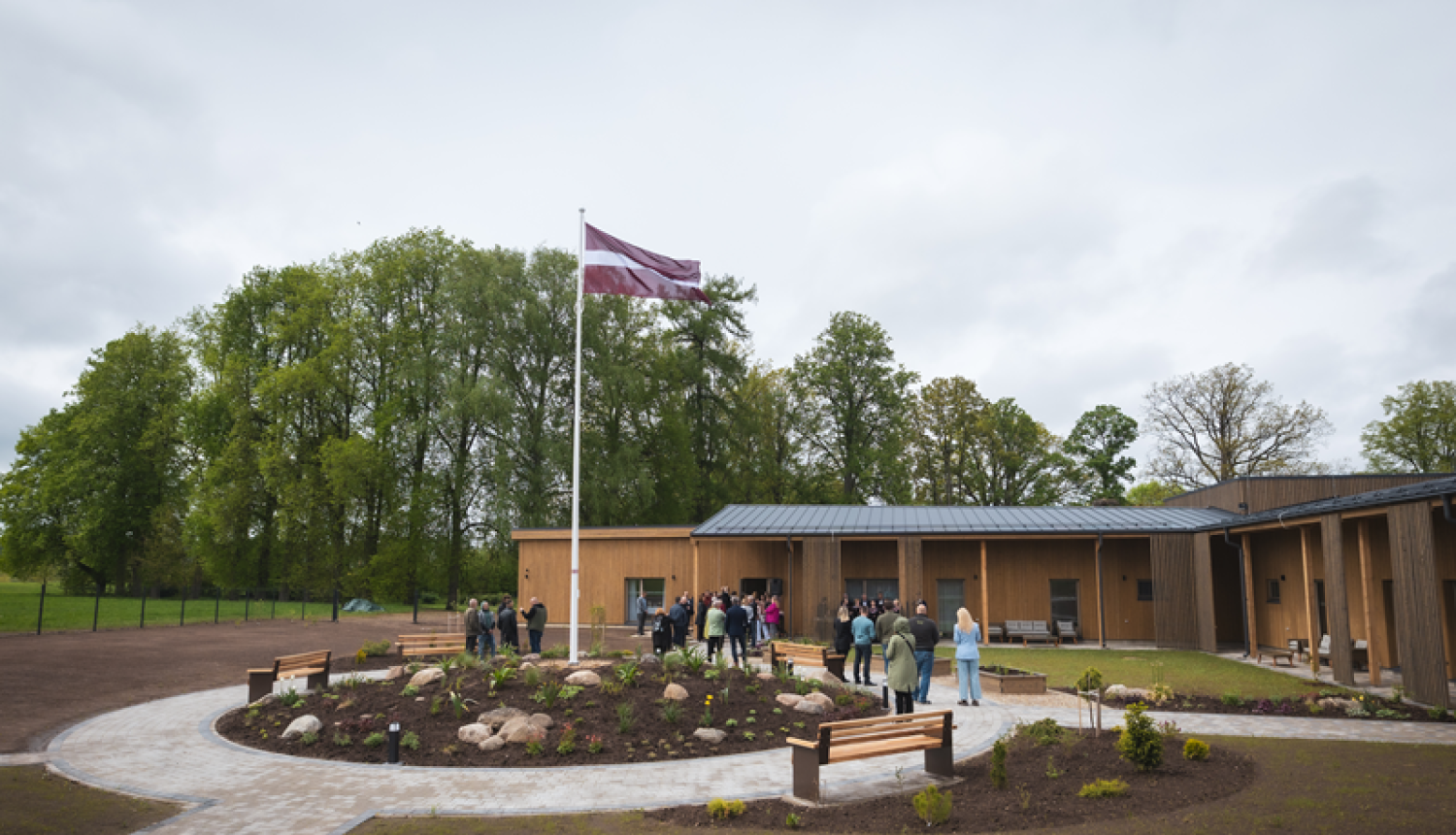 Pansija Rauna no ārpuses. Būna māja, priekšā plīvo Latvijas karogs