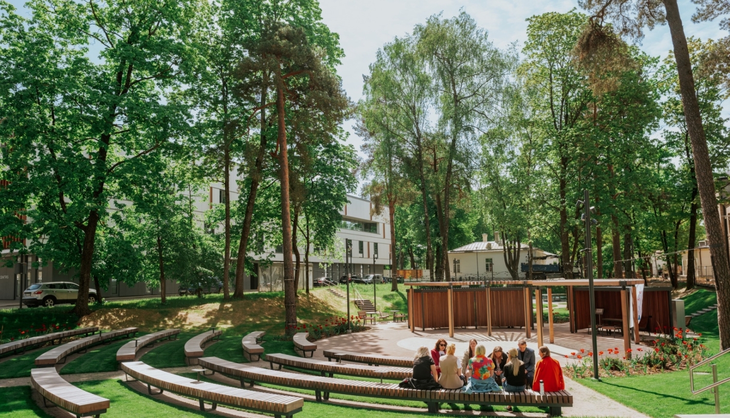 Ārtelpas amfiteātra tipa zona zaļā, koku ieskautā parkā.