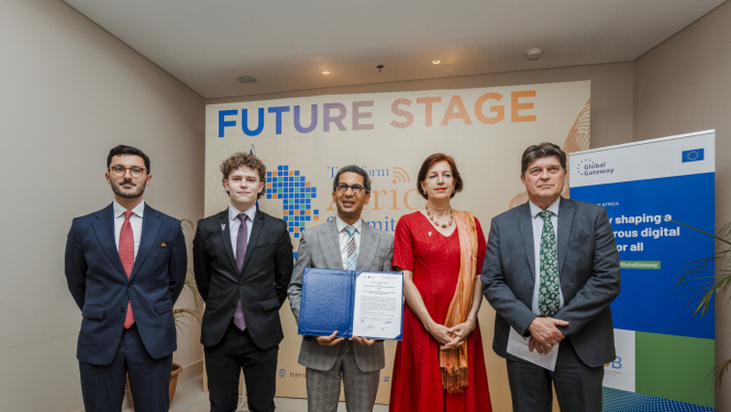 Pieci cilvēki stāv kopā pie sienas ar uzrakstu “Future Stage” un “Transform Africa Summit 2025”, viens tur atvērtu dokumentu mapē. Labajā pusē redzams plakāts ar Eiropas Savienības logotipu un tekstu par digitālās nākotnes veidošanu